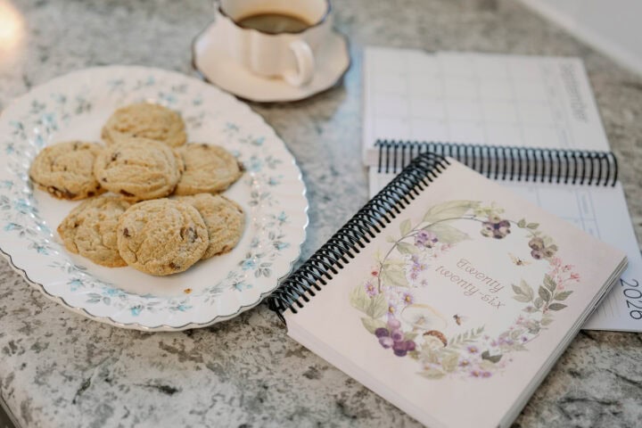The 2026 Classic Weekly Planner and a plate of cookies on a countertop