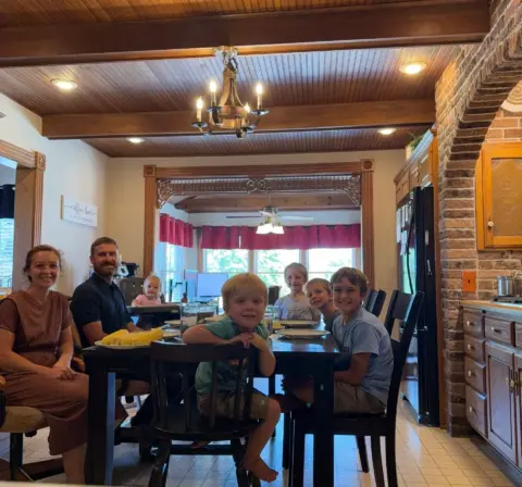 Charlotte's whole family sitting around the dinner table eating supper.