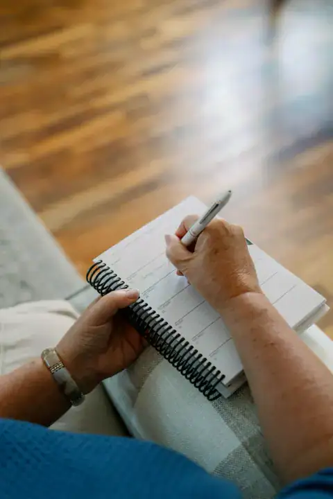 Over the shoulder of Lucretia writing in her weekly planner of this weeks tasks