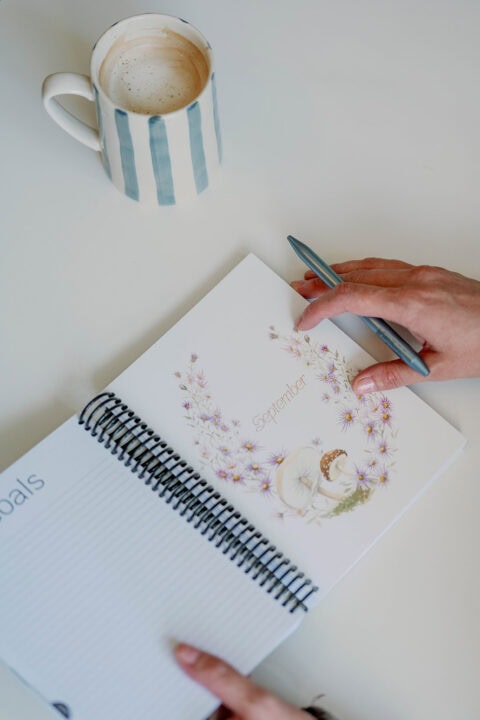 September goals page open in the 2026 Classic Weekly Planner with a hand and coffee mug nearby