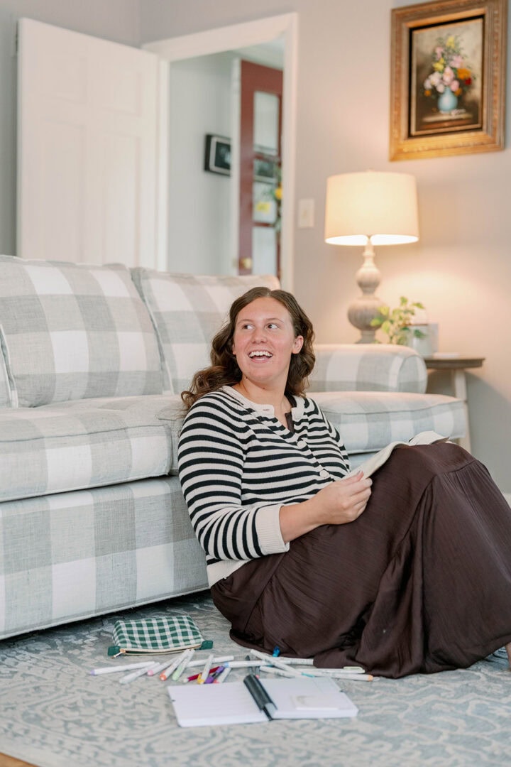Young woman sitting on the floor in the living room with pens and her weekly planner on the floor